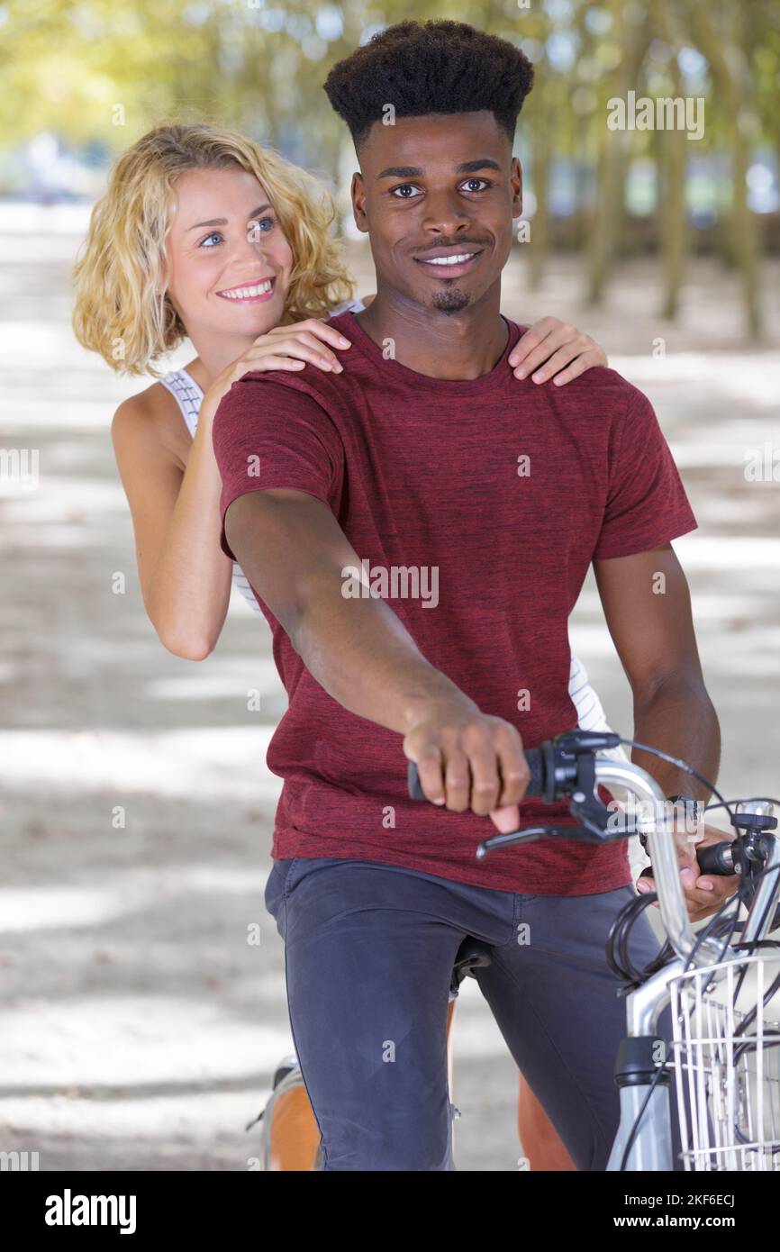 Gemischtes Paar spielt auf einem Fahrrad im Freien Stockfoto