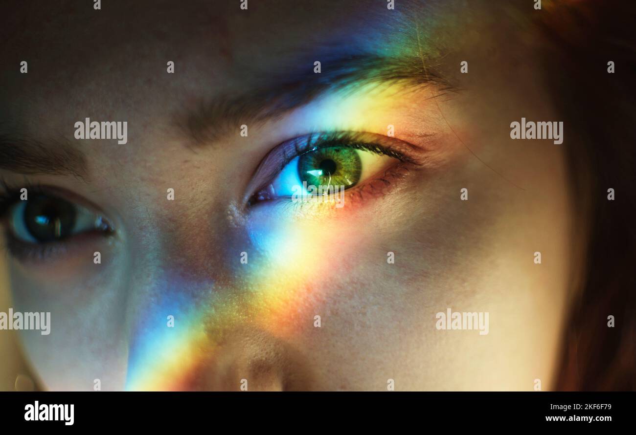 Eine junge Frau mit Regenbogenlicht auf ihrem Gesicht Stockfoto