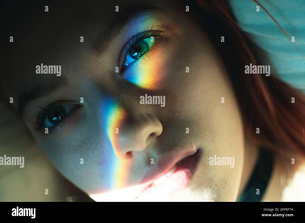 Eine junge Frau mit Regenbogenlicht auf ihrem Gesicht Stockfoto