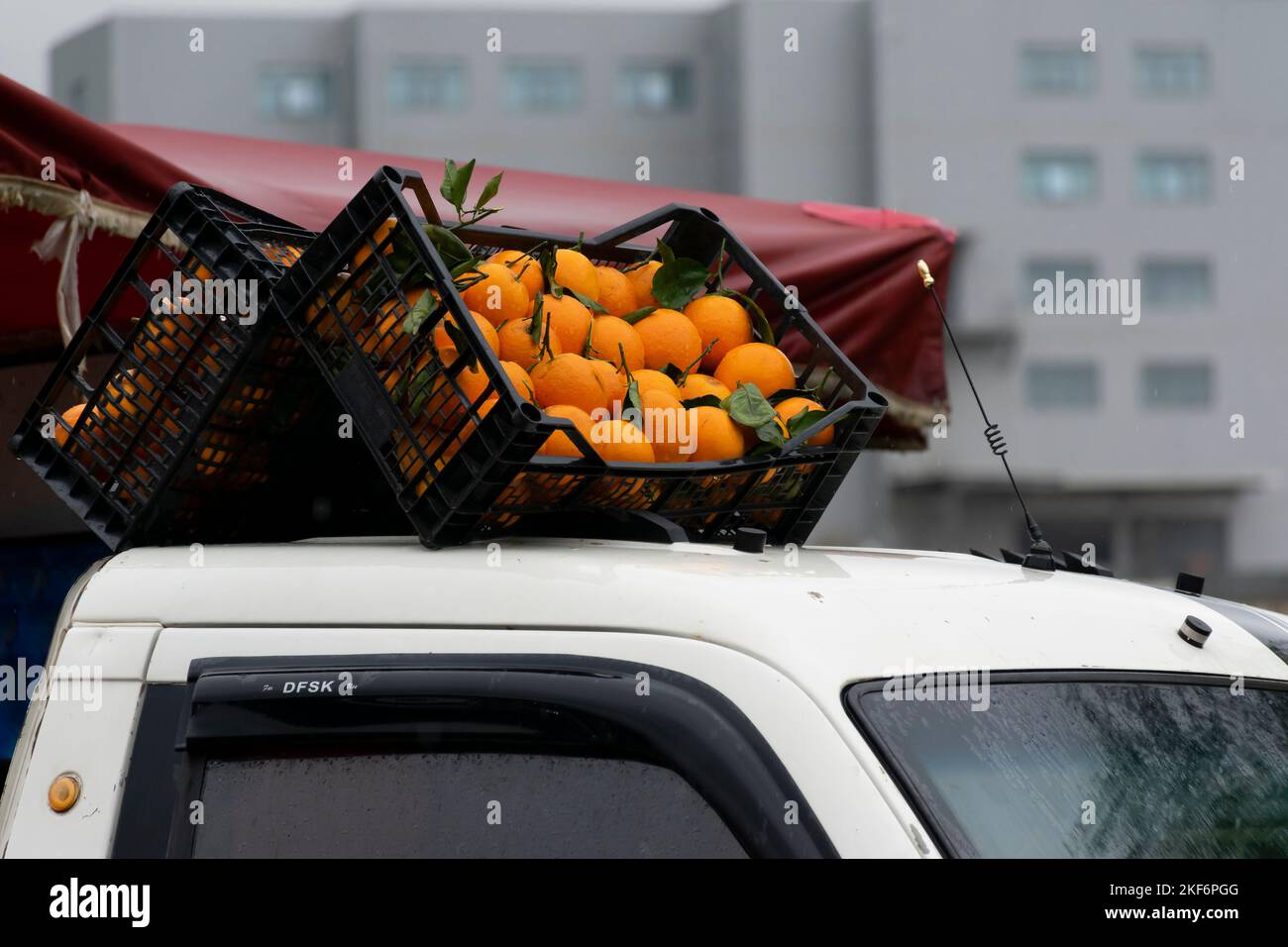 Orangefarbene Kisten auf dem Dach eines Mini-Trucks. Seite an Seite in einer symmetrischen Position. An regnerischen Tagen mit Wassertropfen befeuchten. Rotes Zelt. Stockfoto