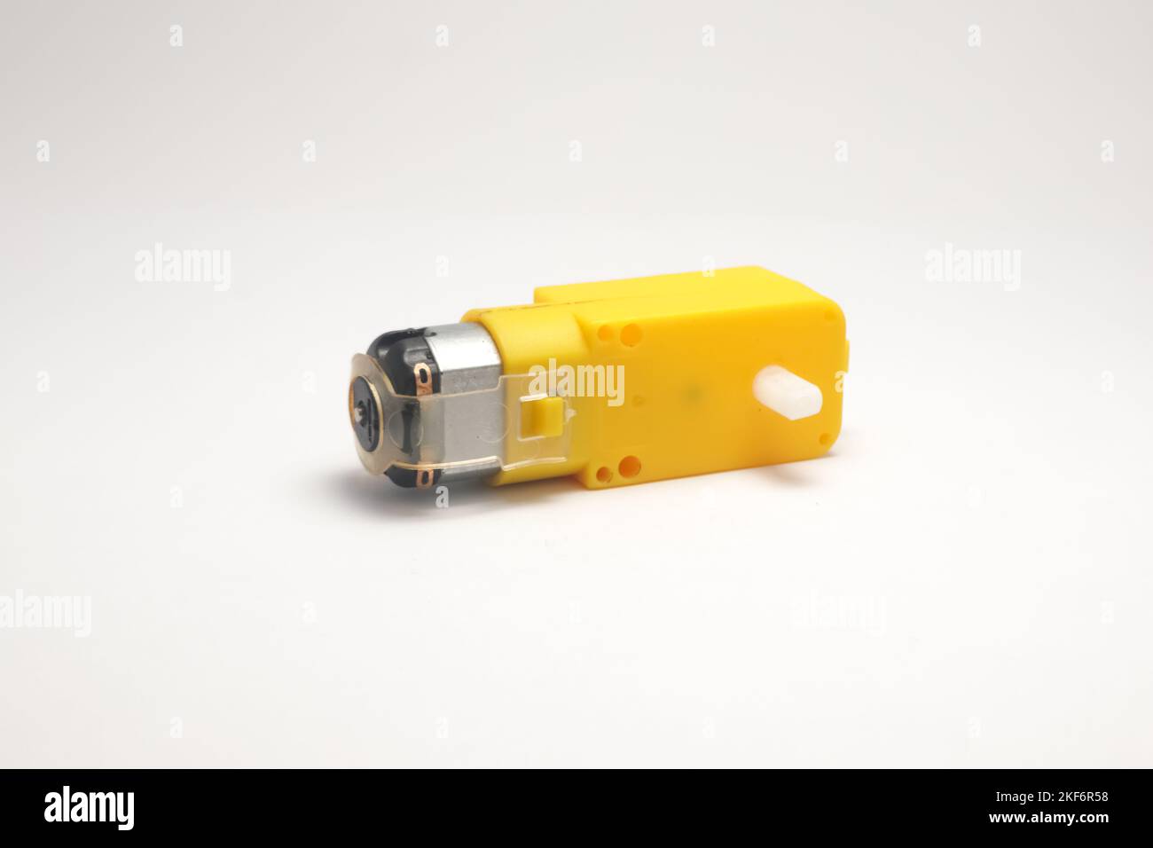 Ein Gleichstrommotor mit einer Steckdose, die mit einer gelben Seitenansicht des Getriebes auf weißem Hintergrund ausgestattet ist. DIY-Materialien für den Elektronik-Bastler. Stockfoto