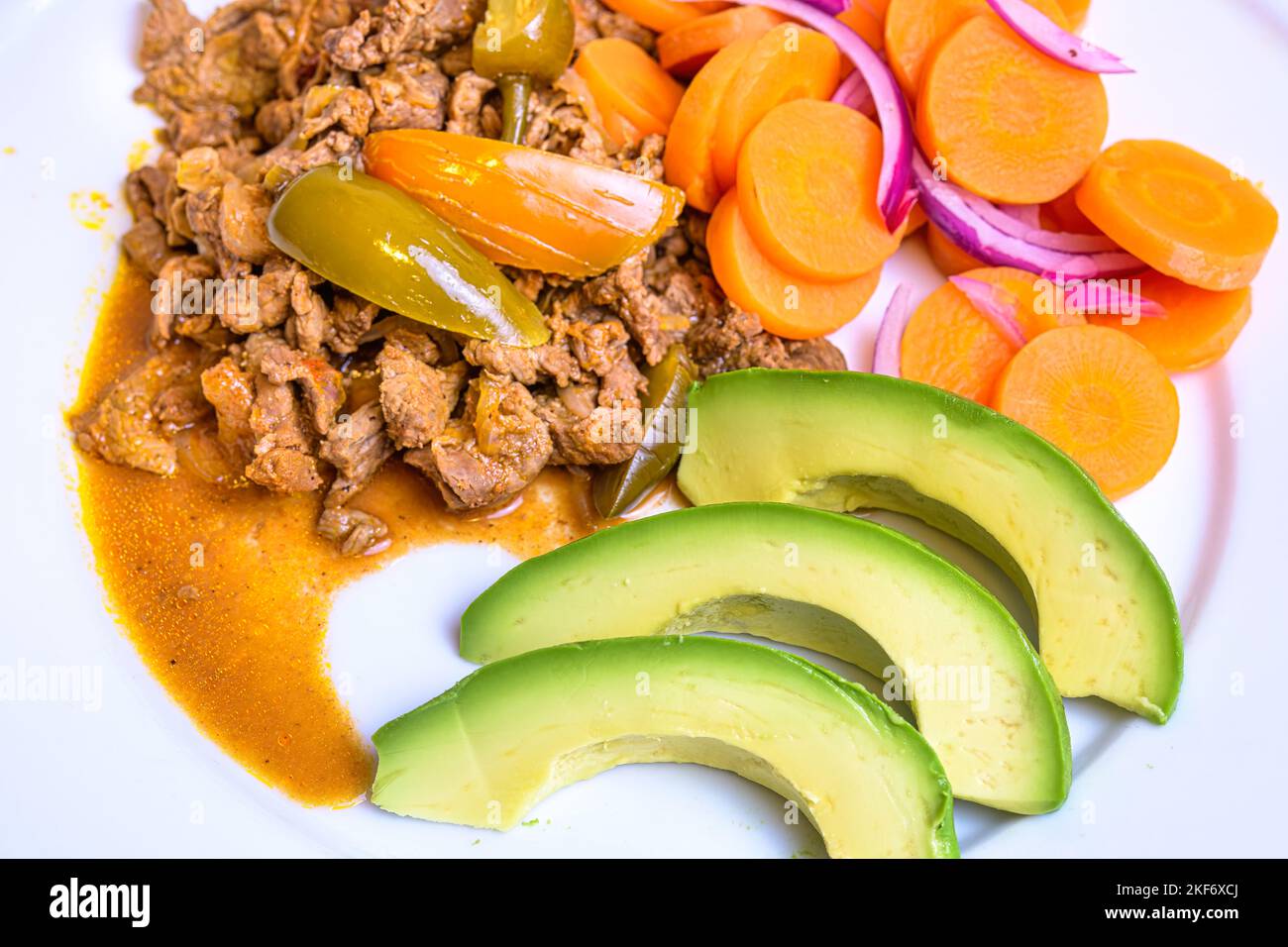 Gekochtes Rindfleisch mit gekochten Karotten und Scheiben Avocado. Stockfoto