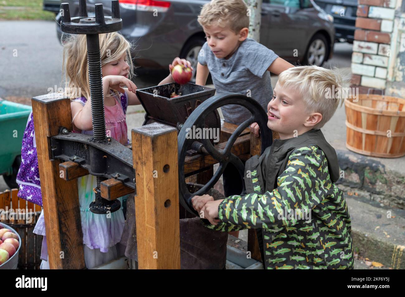Detroit, Michigan - Kinder machen Apfelwein mit einer Apfelpresse auf einem Herbstfest auf der nahen Ostseite von Detroit. Stockfoto