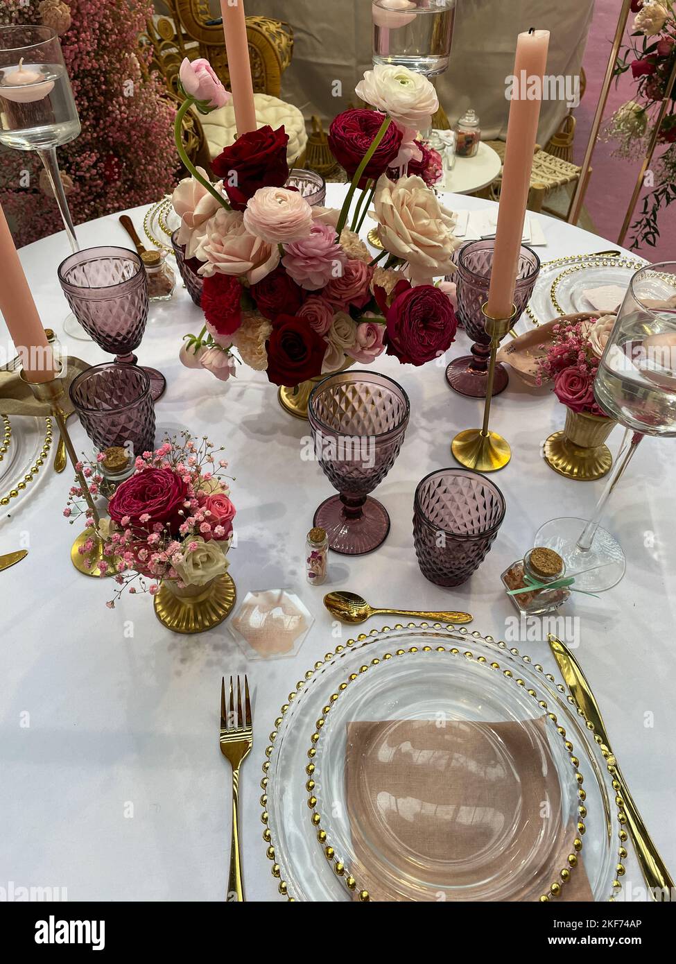 Festliche Tischkulisse in pink-violett-rotem Stil mit Kerzen und Blumen. Stockfoto