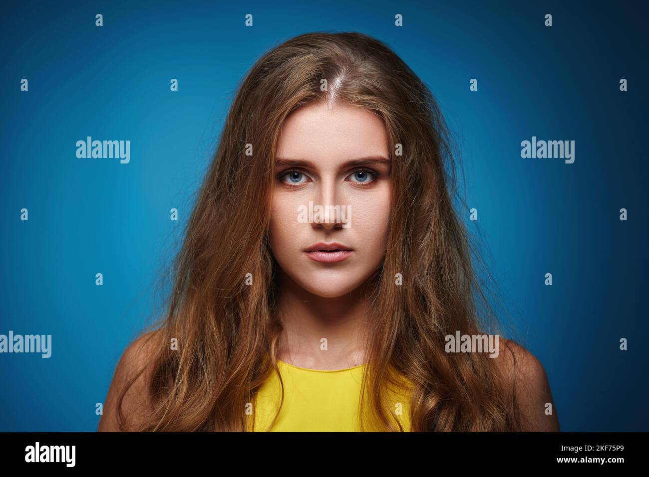 Schöne traurige Frau mit lockigen Haaren auf blauem Hintergrund Stockfoto