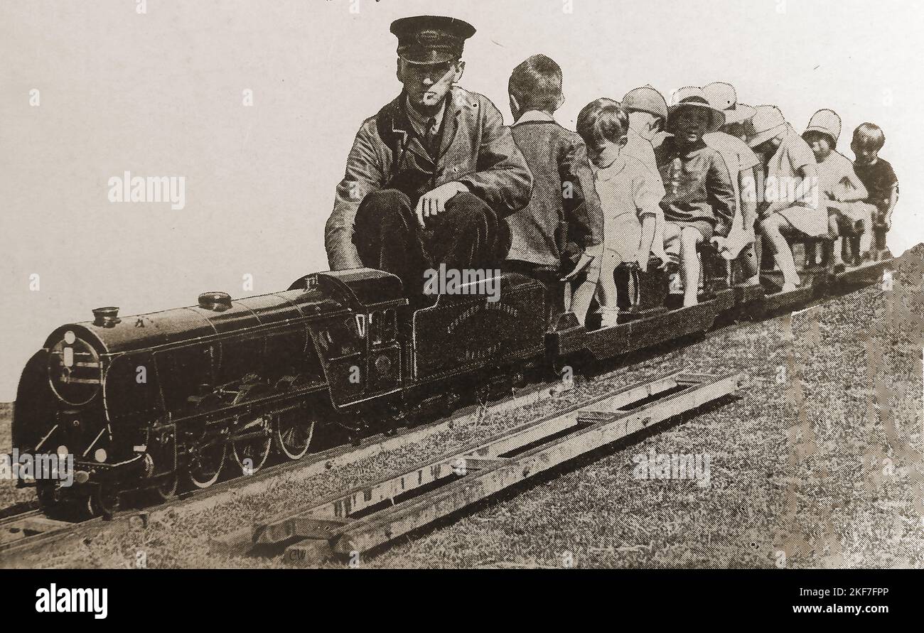 Das Bild der 30er Jahre von britischen Kindern, die eine Zugfahrt auf einem Miniatureisenbahnmotor des Typs King Arthur genießen. Stockfoto