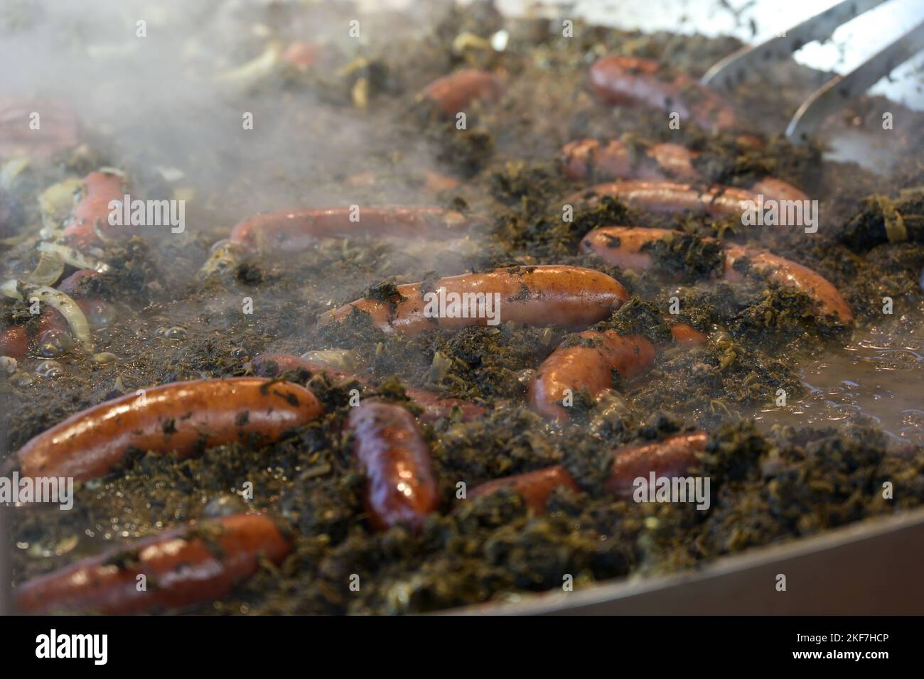 Großer Topf mit dampfendem Grünkohl und Würstchen auf einem Herbstmarkt, deutsches Streetfood in der kalten Jahreszeit, ausgewählter Fokus, enge Fieltiefe Stockfoto