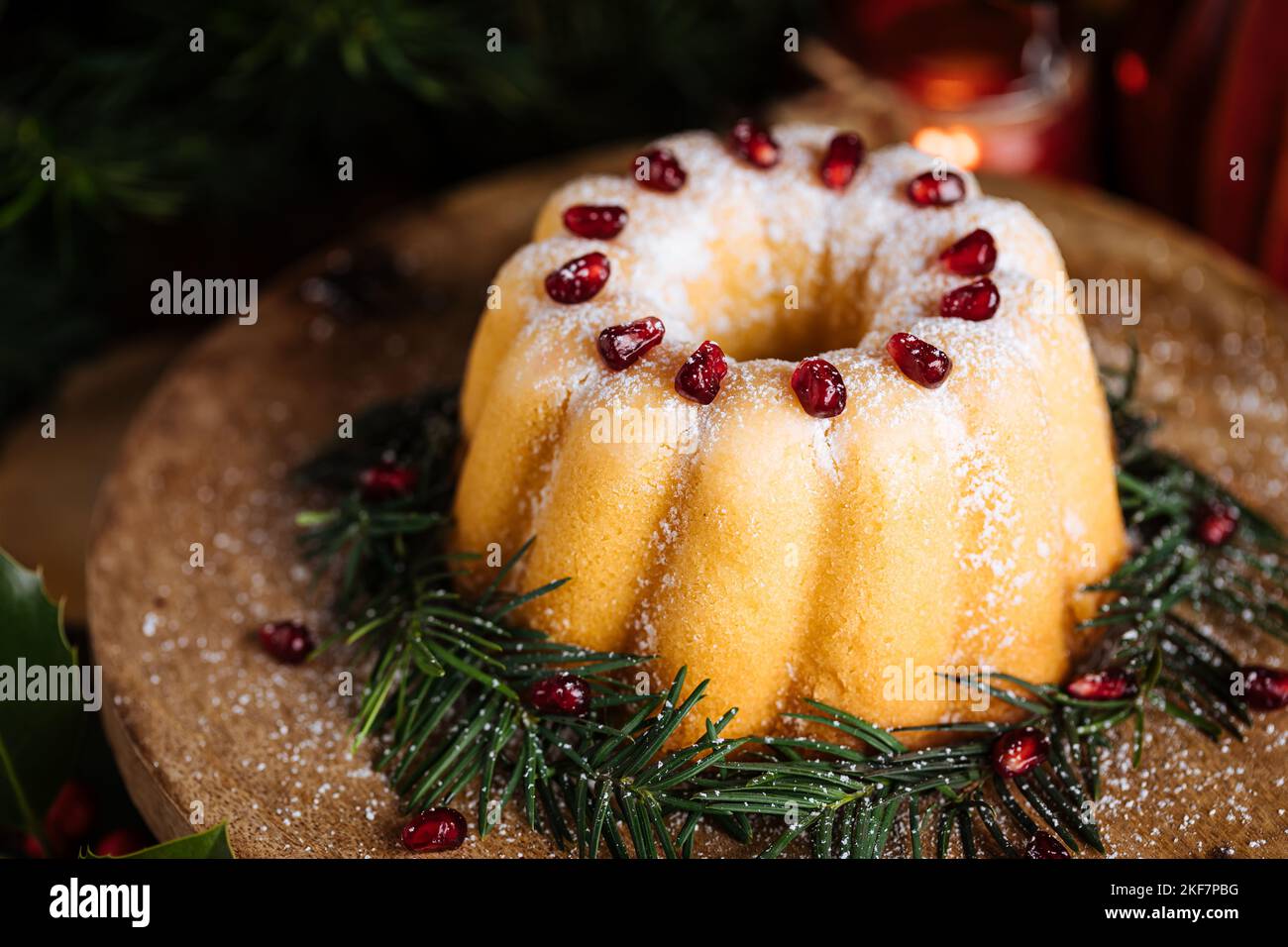 Gebüngelter Kuchen mit Zuckerzuckerung und Granatapfel in Weihnachtsstimmung. Stimmungsvolle Atmosphäre mit Kerzen und Dekoration. Silvester. Nachtisch genannt Stockfoto