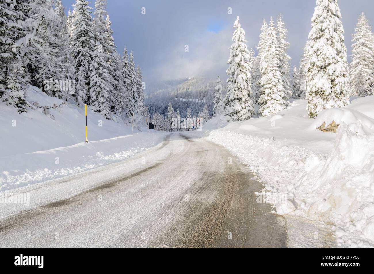 Bergpassstraße durch einen verschneiten Wald im Winter Stockfoto