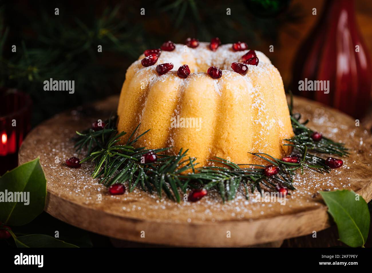 Gebüngelter Kuchen mit Zuckerzuckerung und Granatapfel in Weihnachtsstimmung. Stimmungsvolle Atmosphäre mit Kerzen und Dekoration. Silvester. Nachtisch genannt Stockfoto