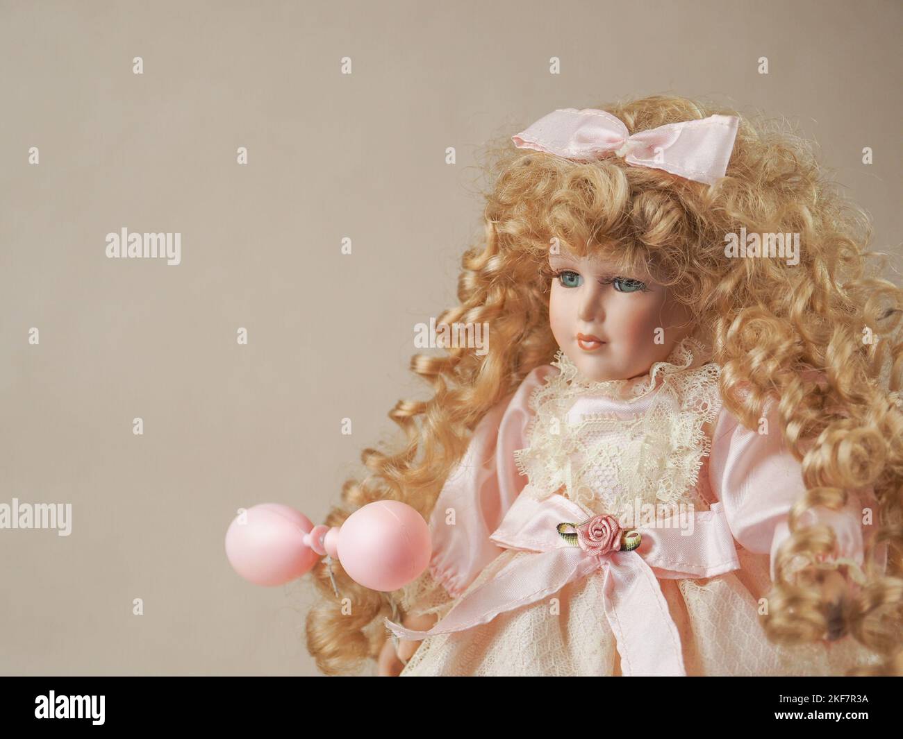 Vintage Porzellan Puppe Mädchen mit blauen Augen mit fließenden lockigen goldenen Haaren und eine Schleife in ihnen in einem hellen Kleid Stockfoto