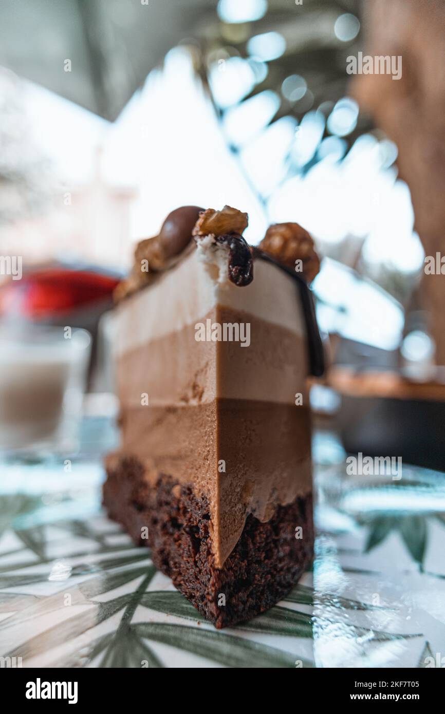 Eine vertikale Aufnahme eines vierlagigen Schokoladenkuchenstückes, das mit Schokolade und Karamell-Popcorn verziert ist Stockfoto