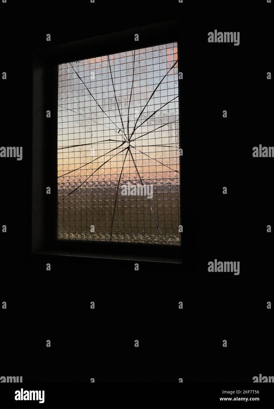 Sonnenuntergang durch rissene Glasscheiben eines antivandal verstärkten Industriefensters Stockfoto