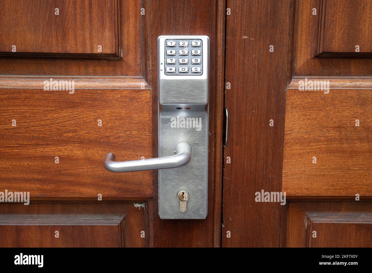 Digitales Türschloss mit Metallgriff an einer Holztür. Sicherheitssystem für Türkennwörter, Codetastatur schließen. Stockfoto