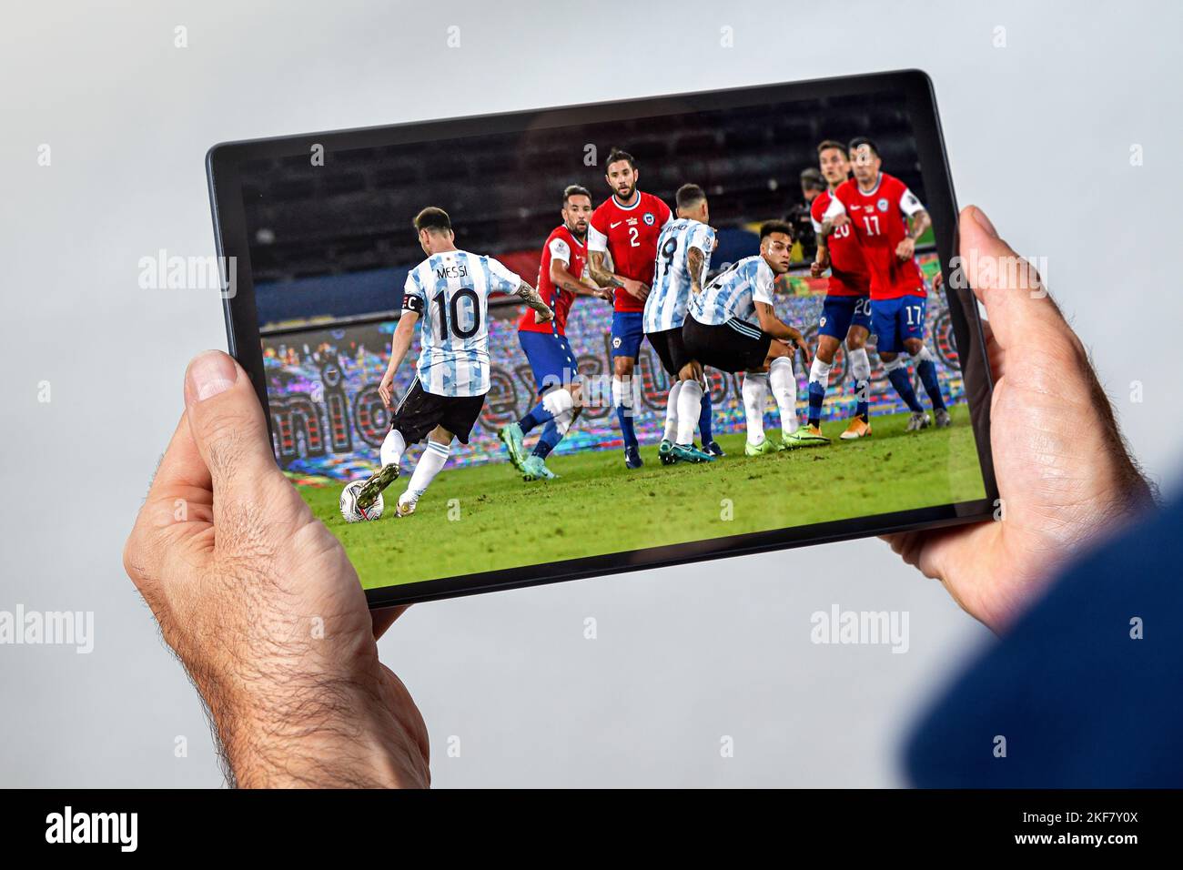 DOHA, KATAR - 15. NOVEMBER 2022: Ein Mann mit einem Tablet und einem Fußballspiel der argentinischen Nationalmannschaft Leo Lionel Messi, der einen Fußballball spielt. Stockfoto