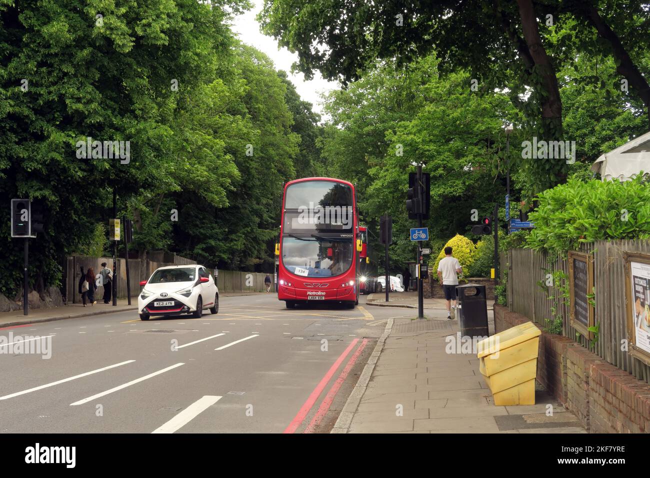 Roter Londoner Bus, der Highgate Woods im Vorort von London Haringey, London, Großbritannien, passiert Mai Stockfoto