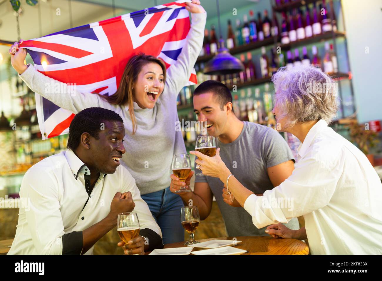 Englische diverse Fußballfans mit Flagge feiern den Sieg der Nationalmannschaft mit einem Pint Bier im Pub Stockfoto