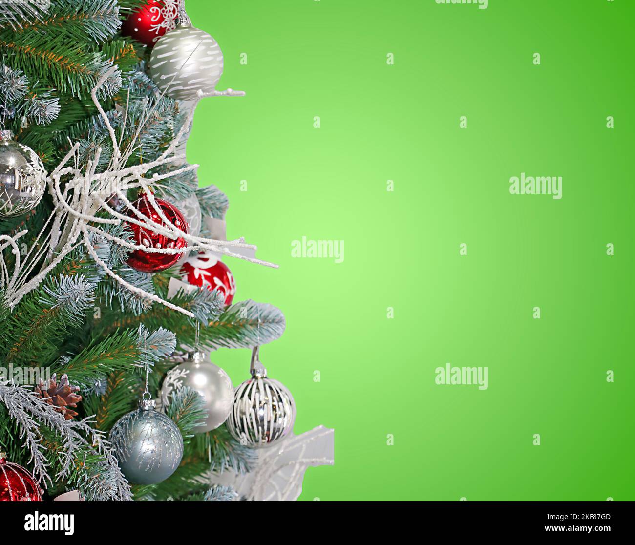 Detail von festlichen Weihnachtsbaum mit Ornamenten und grünem Hintergrund für Kopierraum auf der Seite Stockfoto