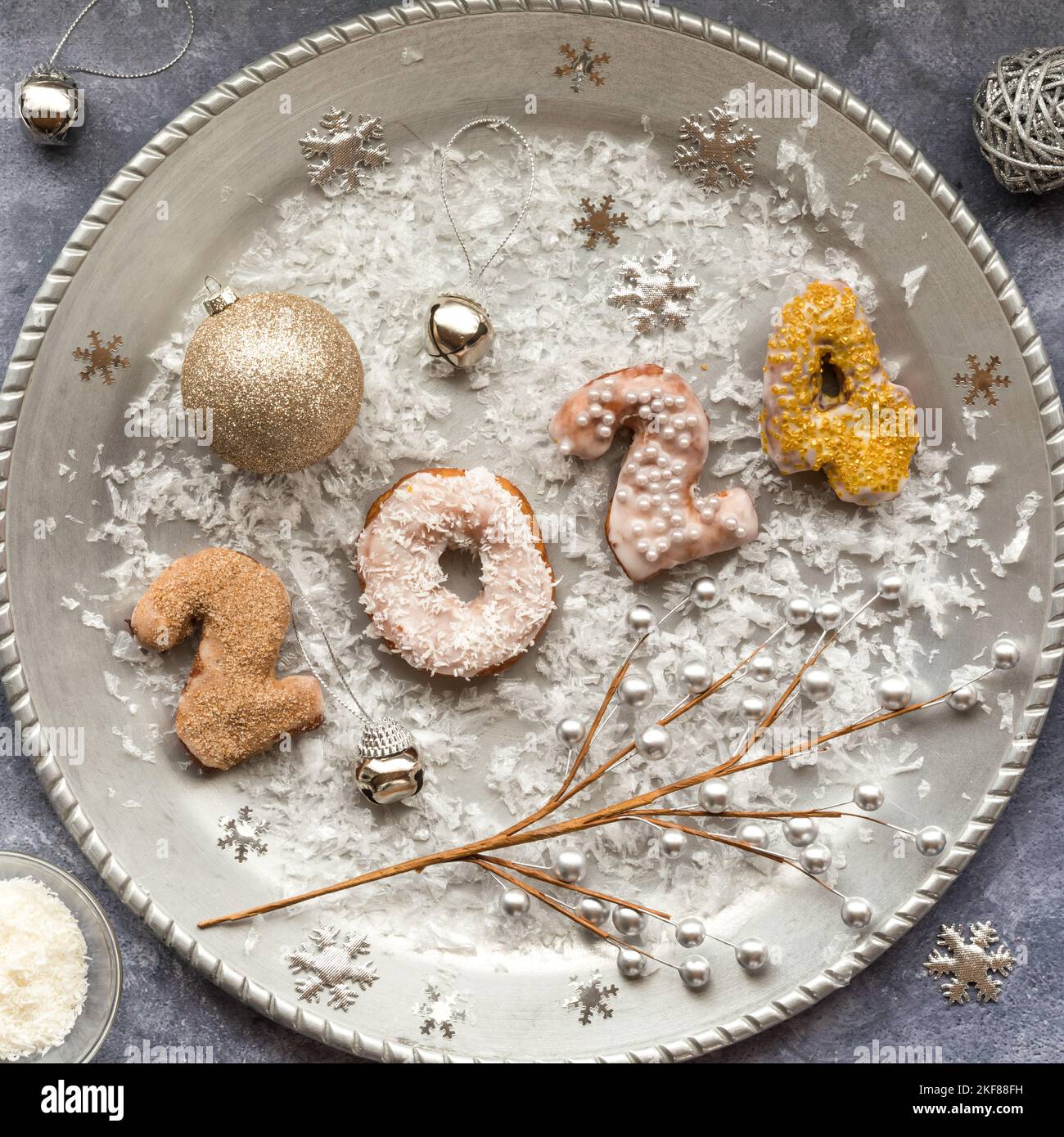 Ein silbernes Tablett mit Dekorationen und Nummerndonuts für das neue Jahr 2024 Stockfoto