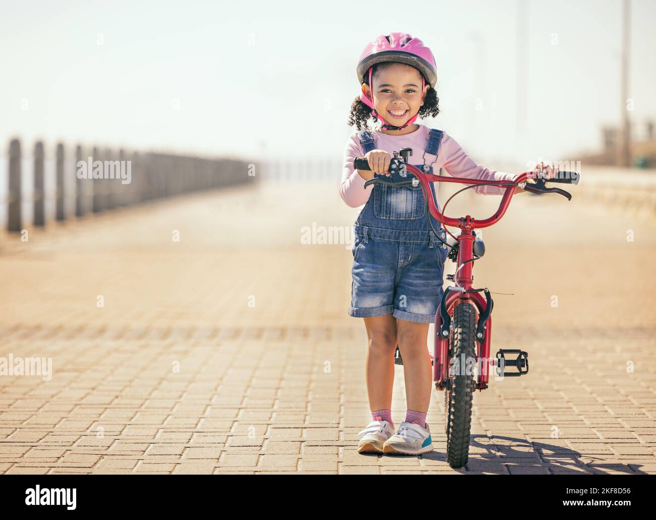 Schwarzes Mädchen, Lernen und Fahrrad für Porträt, Lächeln oder Park Weg mit Sonnenschein, Sicherheit oder Glück. Kind, glücklich und Fahrrad im Training, Outdoor oder Stockfoto