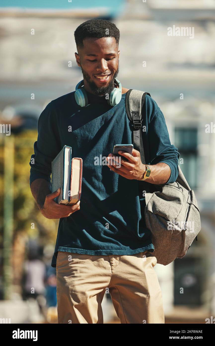 Student, Bildung und Telefon mit einem schwarzen Mann Universitätsschüler, der auf dem Campus läuft, während er eine Textnachricht tippt. Soziale Medien, Kommunikation und Kontakt Stockfoto