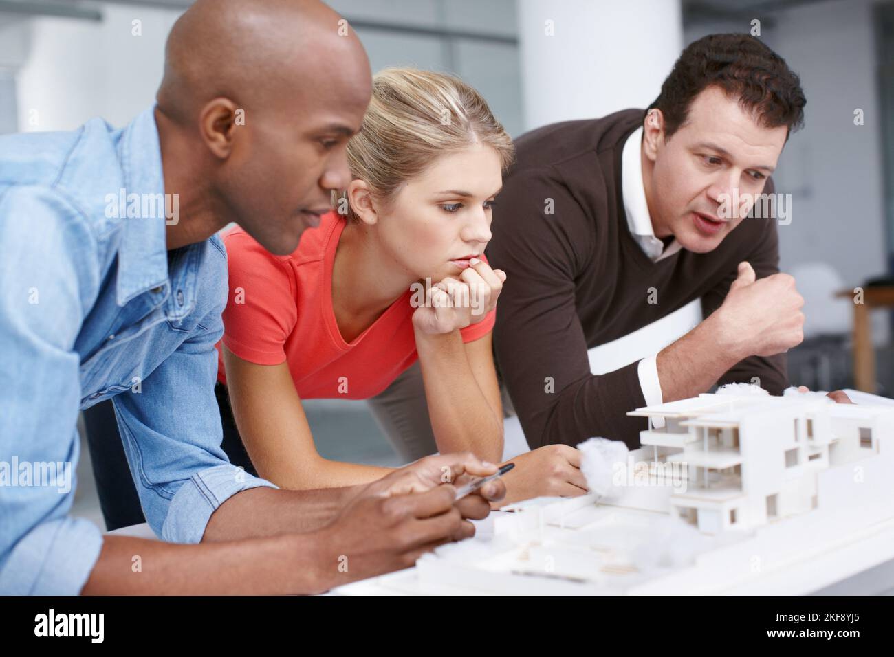 Erstklassige Designer. Ein Team von Architekten, die bei der Zusammenarbeit an einem Architekturmodell nachdenklich aussehen. Stockfoto