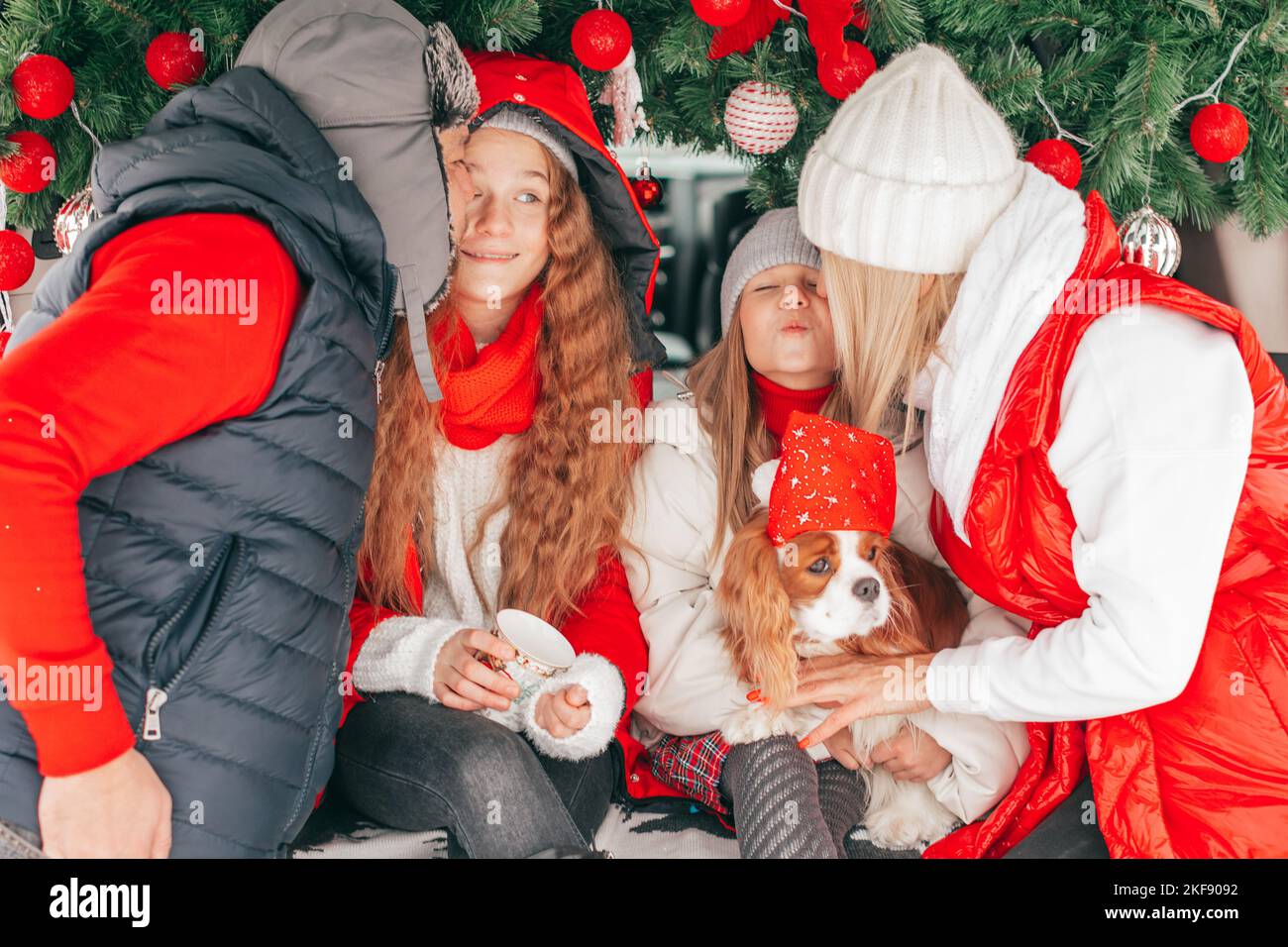 Freundliche Familie ist mit Weihnachtsfeier im Kofferraum des Autos im Wald, Papa, Mama und zwei Mädchen glücklich, Zeit mit Hund während der Winterferien zu verbringen. Stockfoto