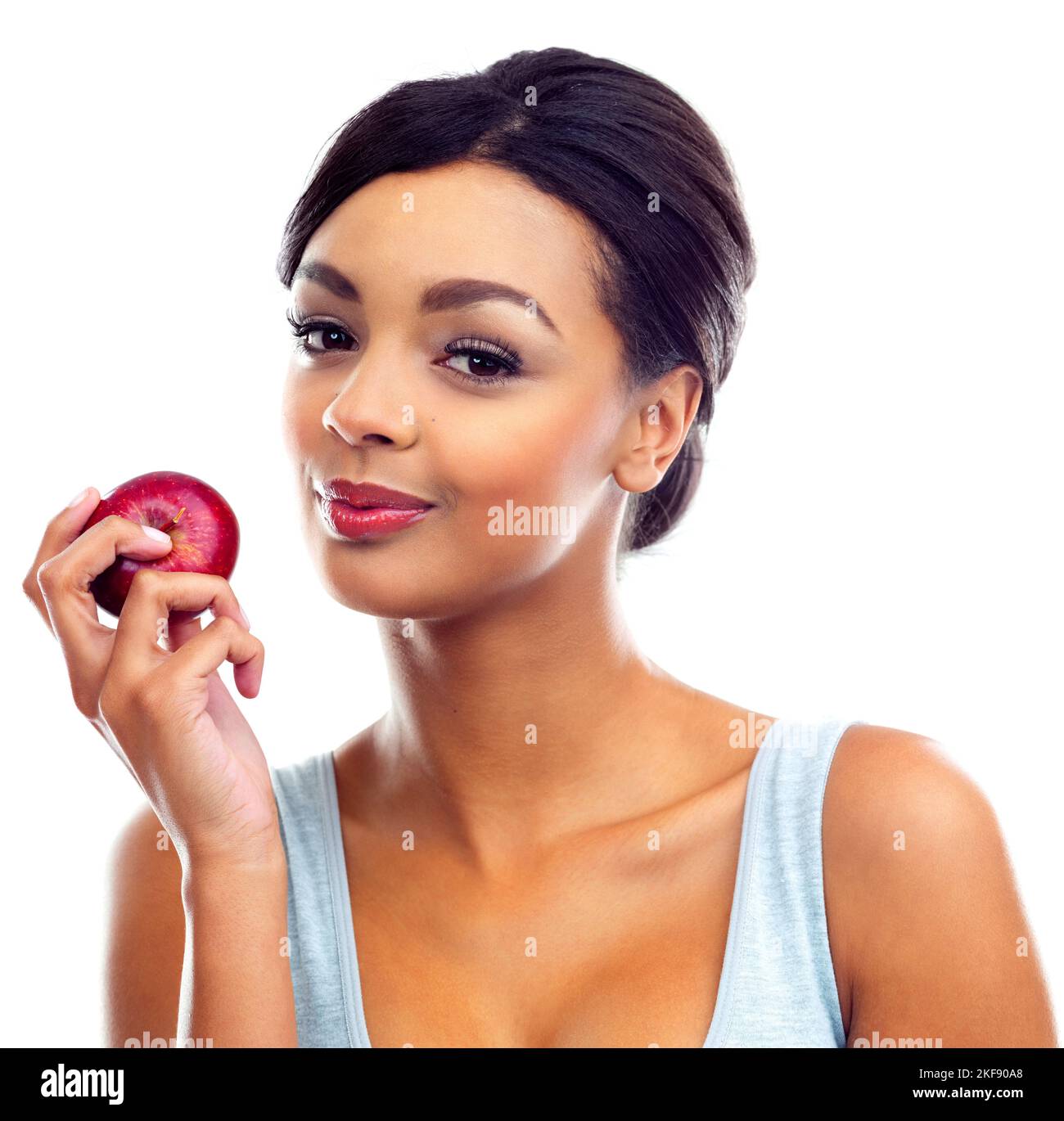 Alles ist möglich, wenn Sie Sport treiben und gesund essen. Eine junge Frau in Turnkleidung, die einen Apfel hält und die Kamera anlächelt. Stockfoto