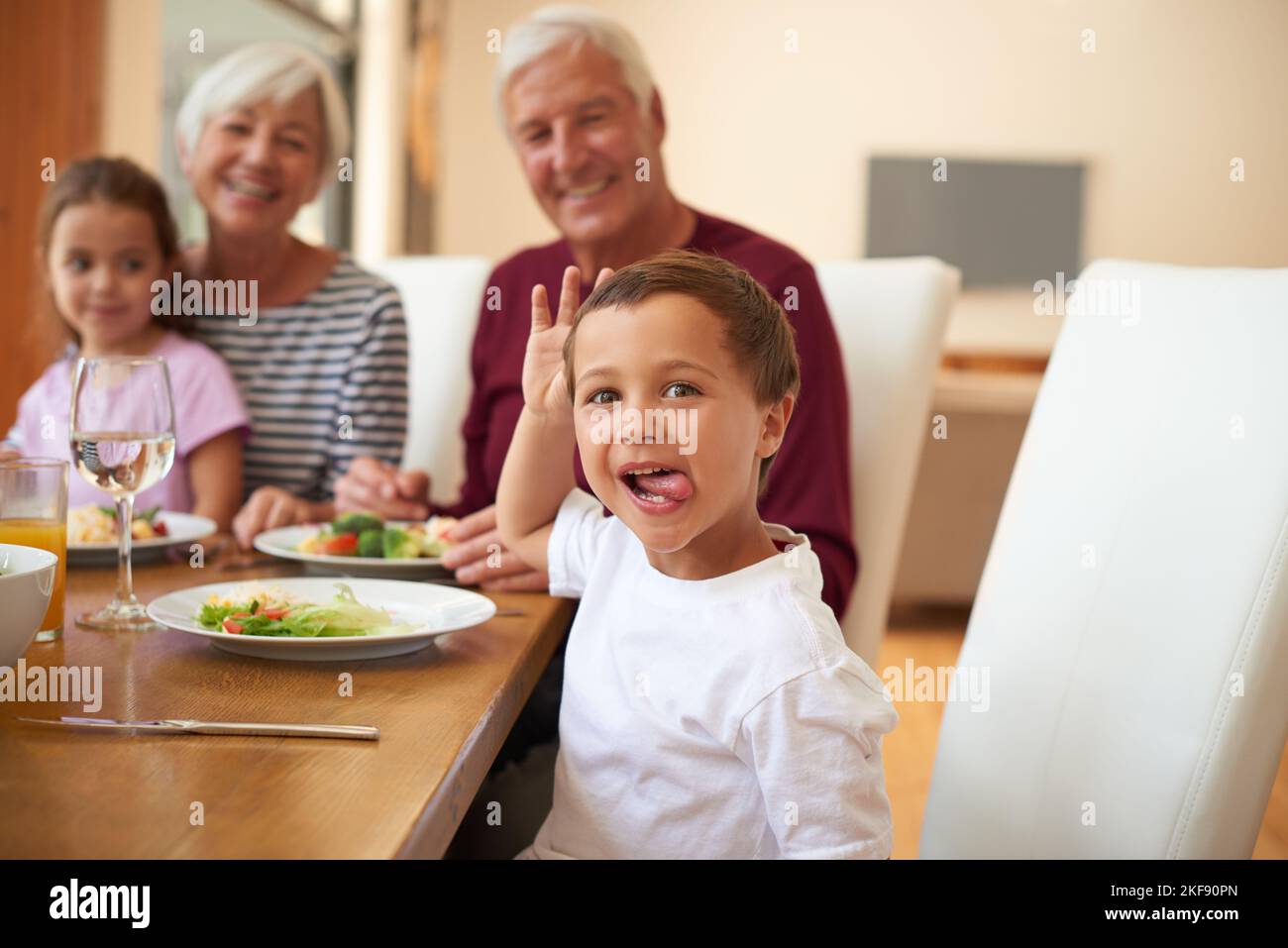 Das war D-licious. Porträt eines kleinen Jungen, der mit seinen Großeltern zu Abend gegessen hat. Stockfoto