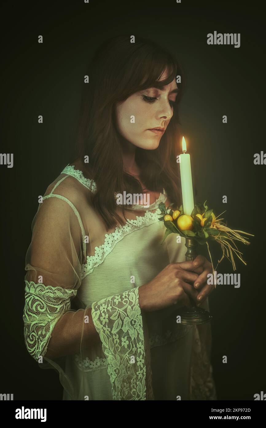 Dunkle Frau mit einer Kerze. Schwarzer Hintergrund Stockfoto