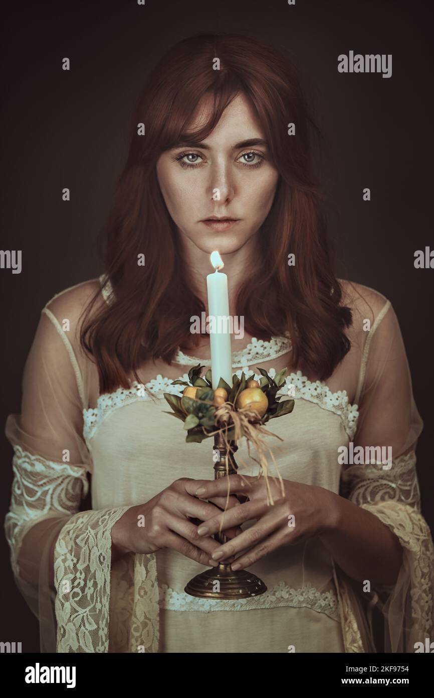 Geheimnisvolle Frau mit Kerze. Dunkelheit und Schatten Stockfoto
