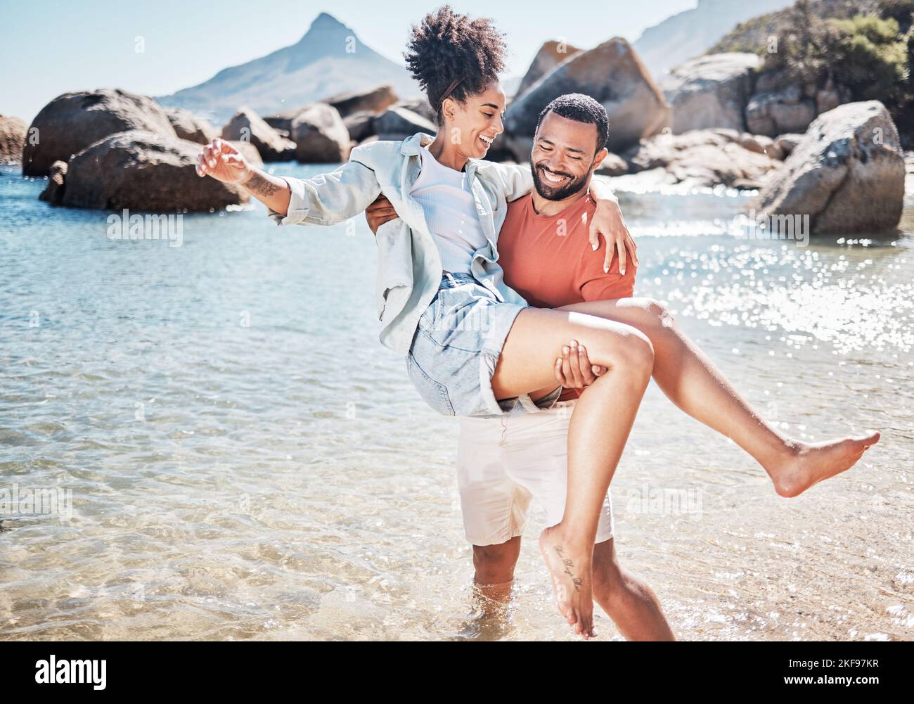 Paar, Strand und Mann tragen Frau für die Liebe, Ehe Unterstützung und lustige Urlaub. Reisen, gute Zeit zusammen und Sommerfreiheit in Hawaii Stockfoto