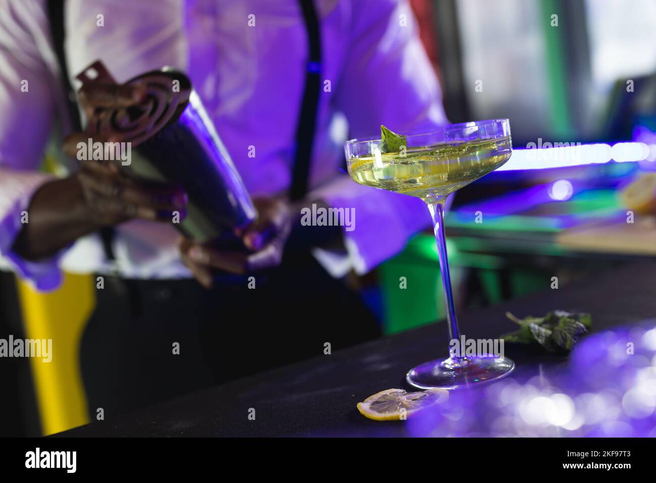 Der mittlere Teil des afroamerikanischen Barkeepers bereitet einen grünen Cocktail an einer Bar zu, selektiver Fokus Stockfoto