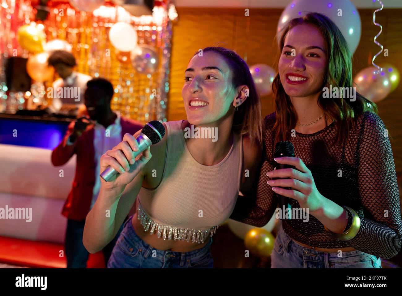 Zwei fröhliche weiße Freundinnen, die Karaoke in einer Nachtklubbar singen Stockfoto