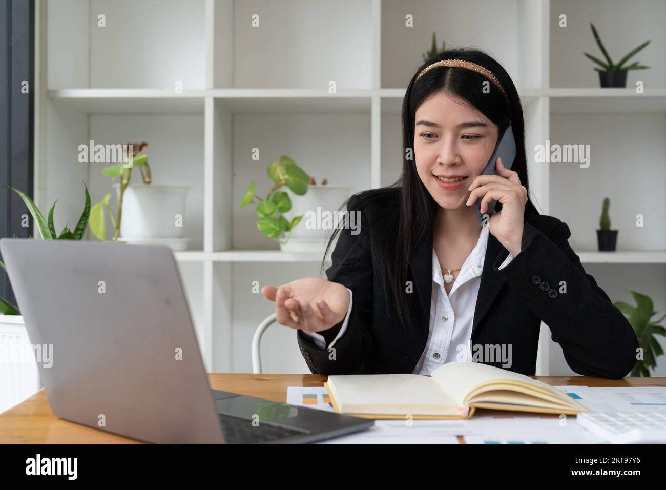 Young Office Asian Frau im Gespräch mit jemandem auf ihrem Handy, während Blick in die Ferne mit glücklichen Gesichtsausdruck. Stockfoto