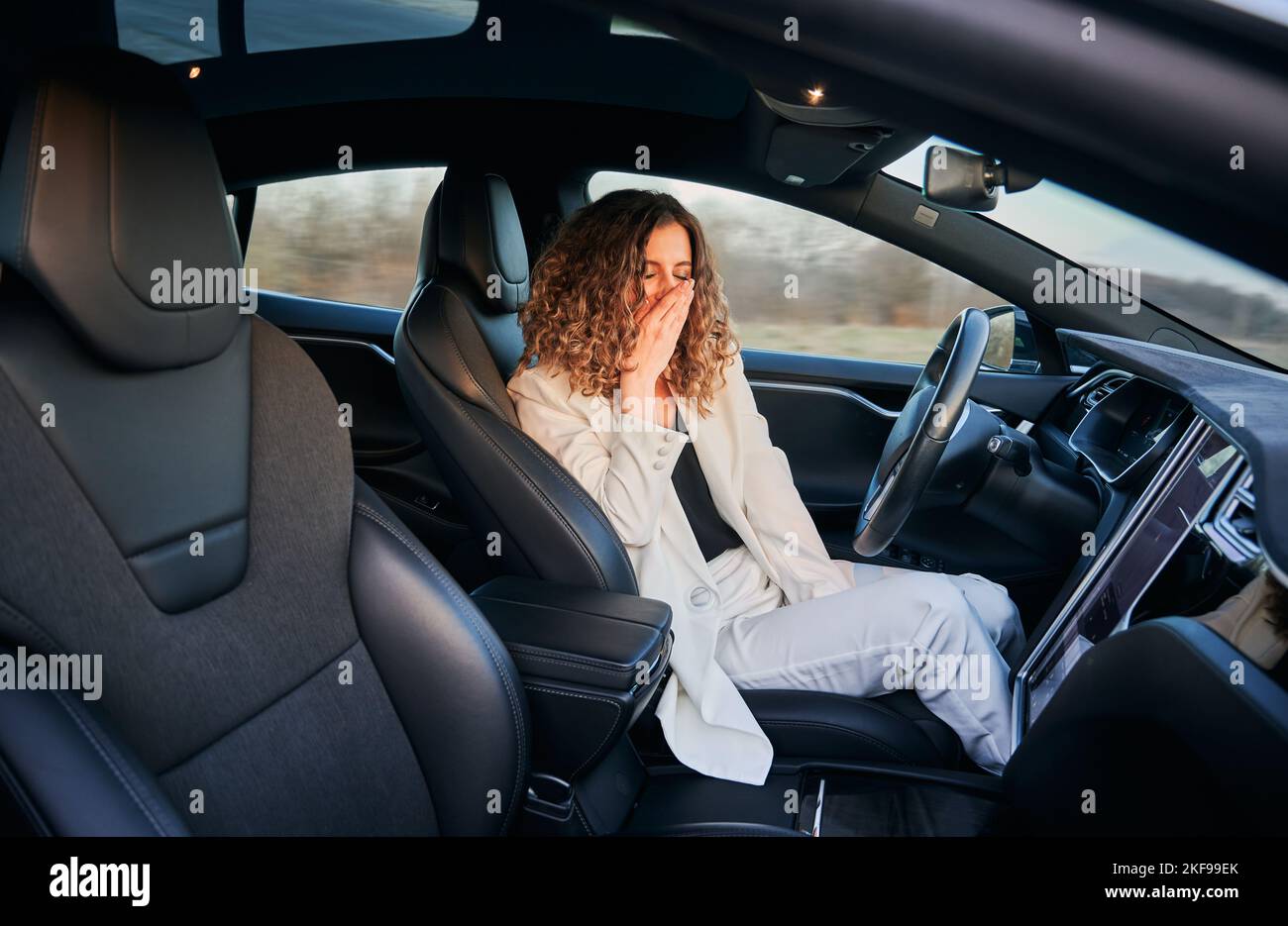 Müde Geschäftsfrau Gähnen während Auto selbst fahren in fortgeschrittenen Auto Fahrzeug, Caucaisan weibliche Besitzer haben Autopilot-Reise mit Freisprechmodus in autonomen Automobil Stockfoto