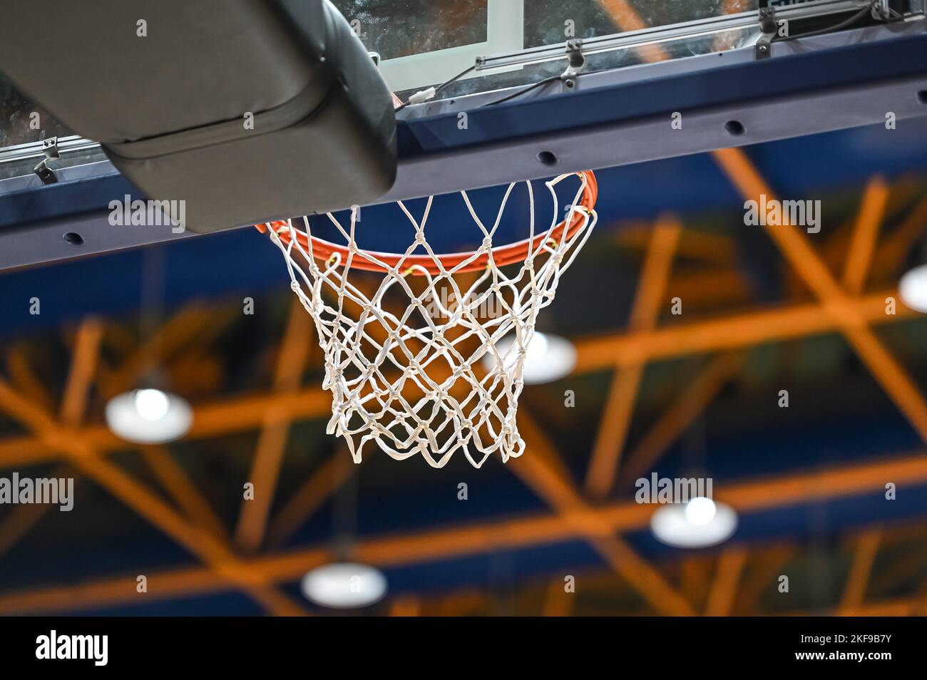Basketball-Korbnetz aus weißem Seil von unten gegen das Stadiondach Stockfoto