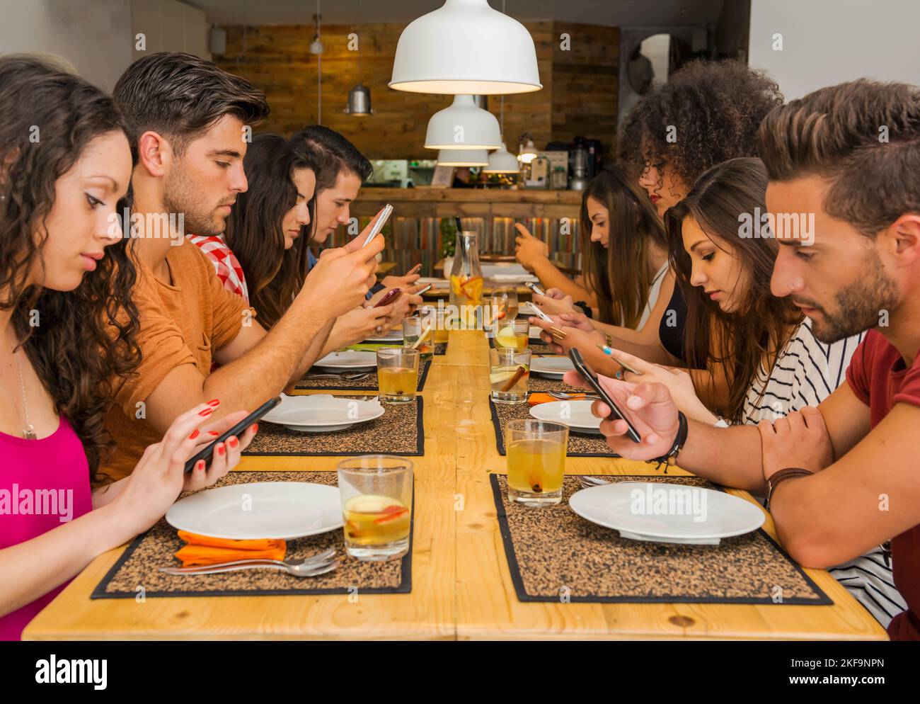 Gruppe von Freunden in einem Restaurant mit allen Menschen auf dem Tisch auf dem Handy Stockfoto