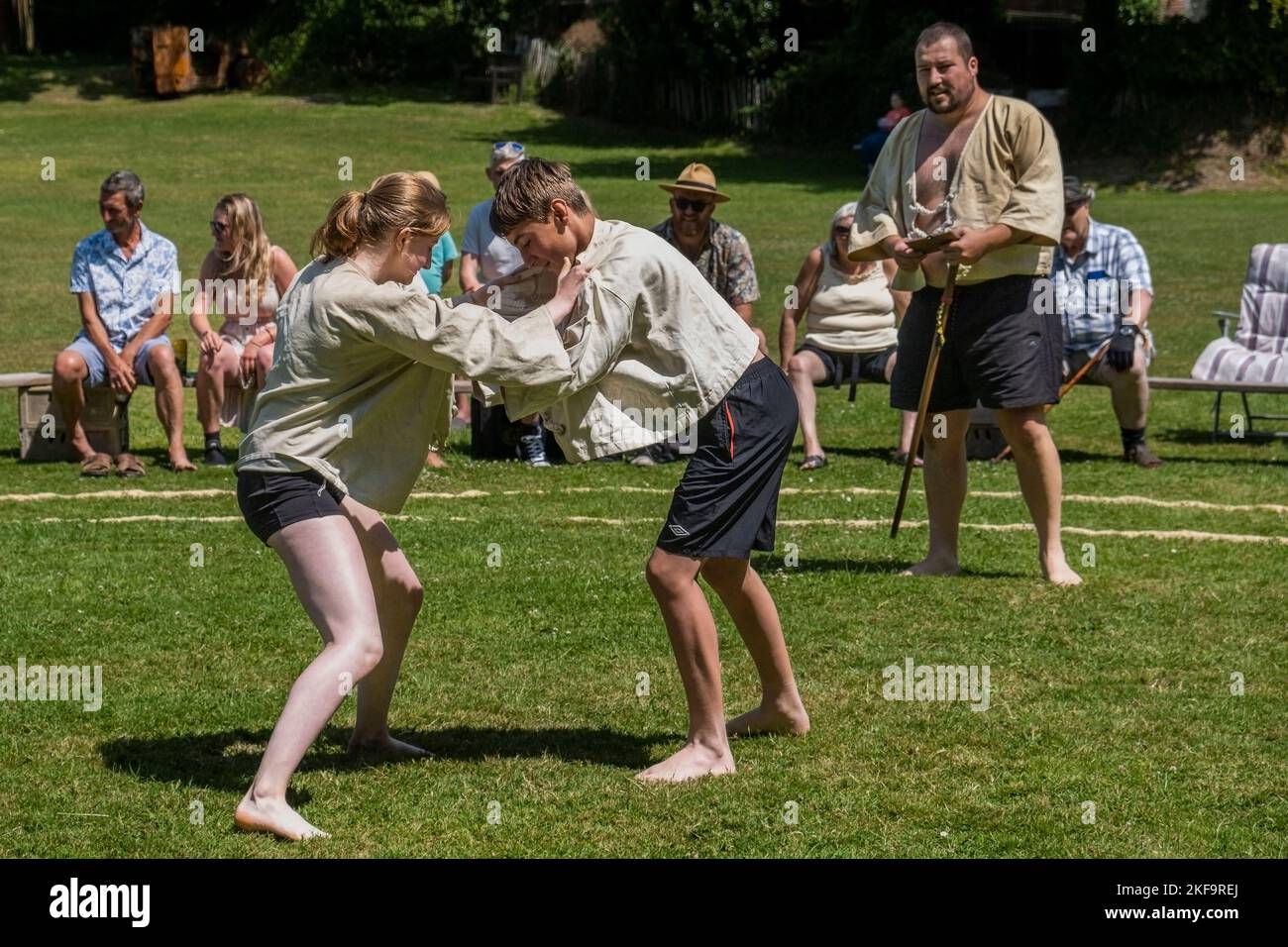 Ein Richterschiedsrichter Stickler beobachtet ein junges Mädchen im Teenageralter, das mit einem Jungen auf dem malerischen Amboss beim Grand Cornish Wrestling Turnier kämpft Stockfoto