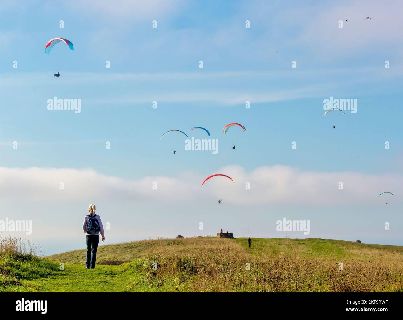 Walker on Beachy Head, Eastbourne, East Sussex, mit Gleitschirmfliegern oben Stockfoto