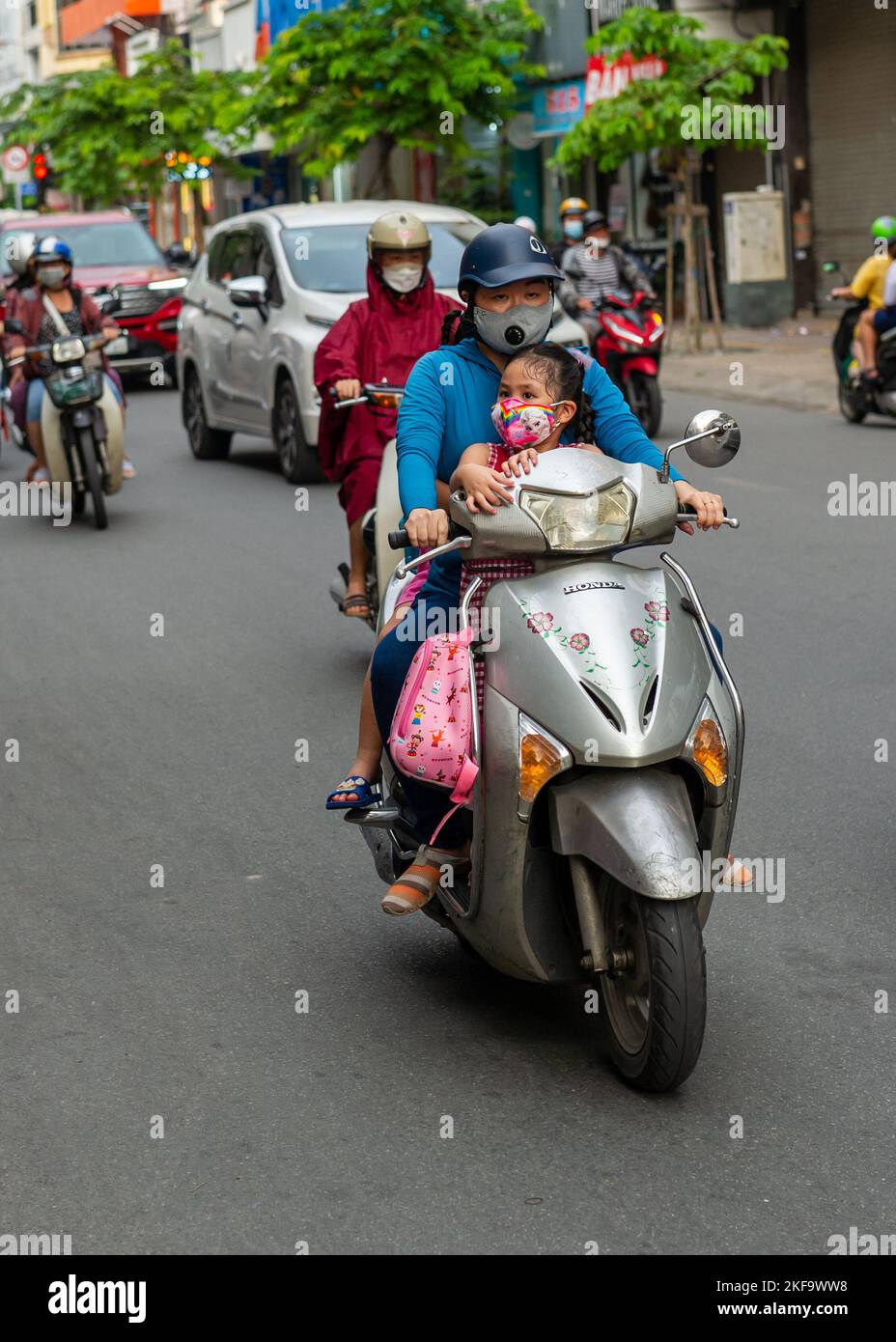 Saigon Street Life. Eltern, die mit ihren Kindern in Ho-Chi-Minh-Stadt auf Motorrädern fahren Stockfoto