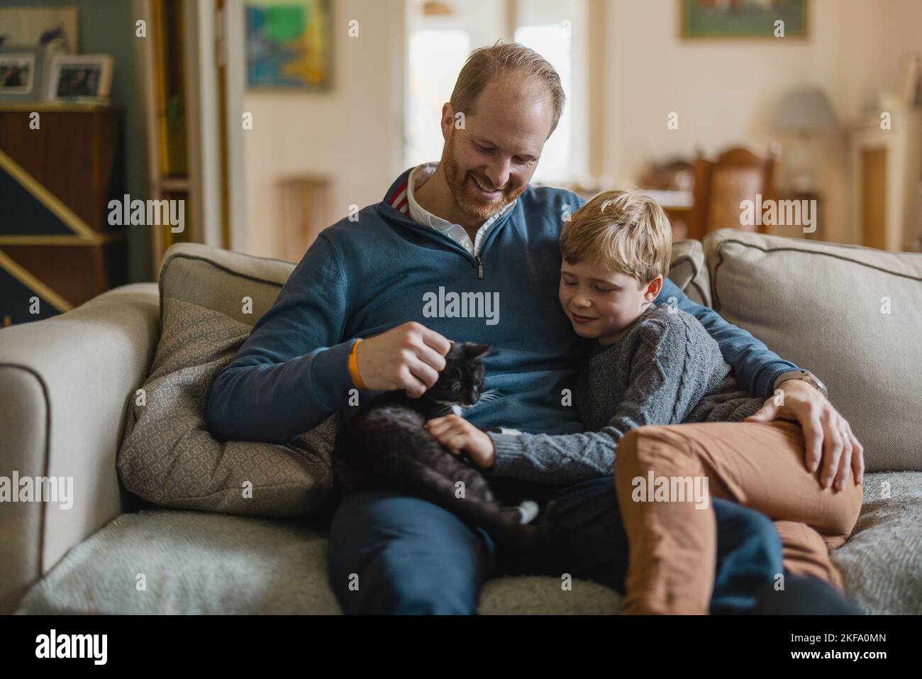 Papa mit Sohn sitzt zu Hause auf dem Sofa Stockfoto