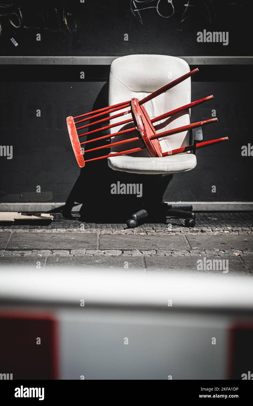 Ein roter Holzstuhl auf einem weißen Drehstuhl, der auf der Straße verlassen wurde Stockfoto