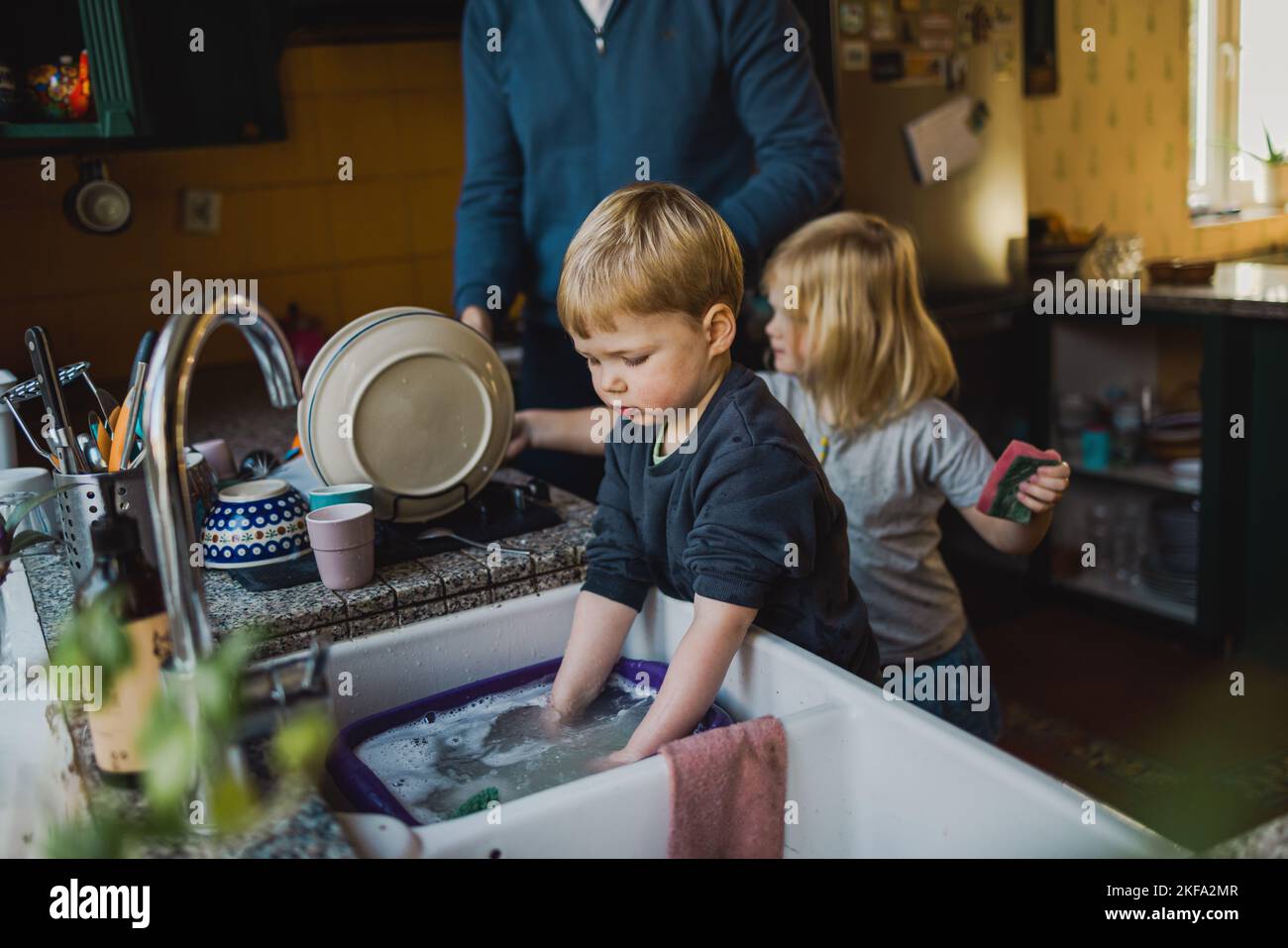 Kinder helfen dem Vater beim Abwaschen in der Küche Stockfoto
