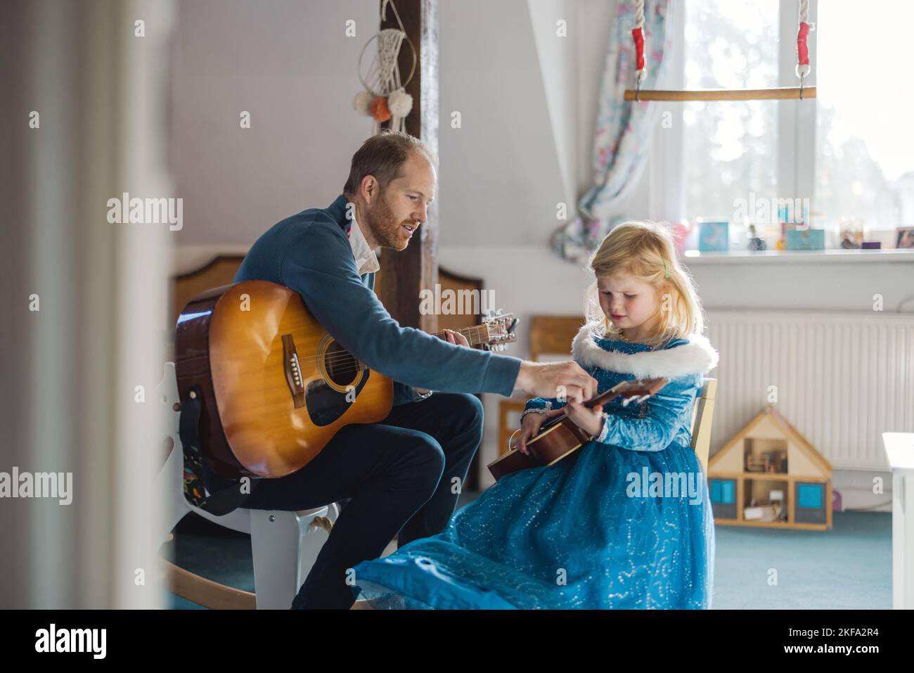 Papa lehrt seine Tochter, wie man Gitarre spielt Stockfoto