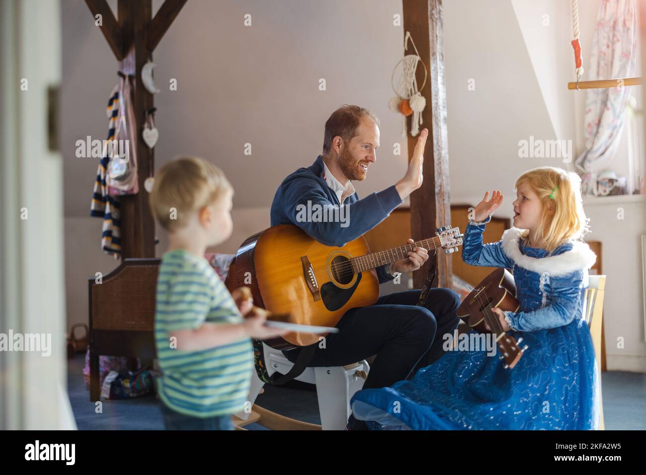 Papa lehrt seine Kinder, wie man Gitarre spielt Stockfoto