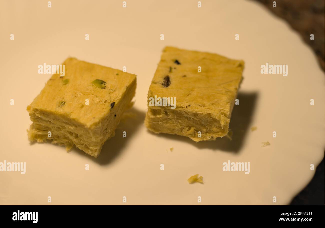 Zwei Stücke indischer Süßigkeiten, Soan Papdi, serviert auf einem weißen Teller. Stockfoto