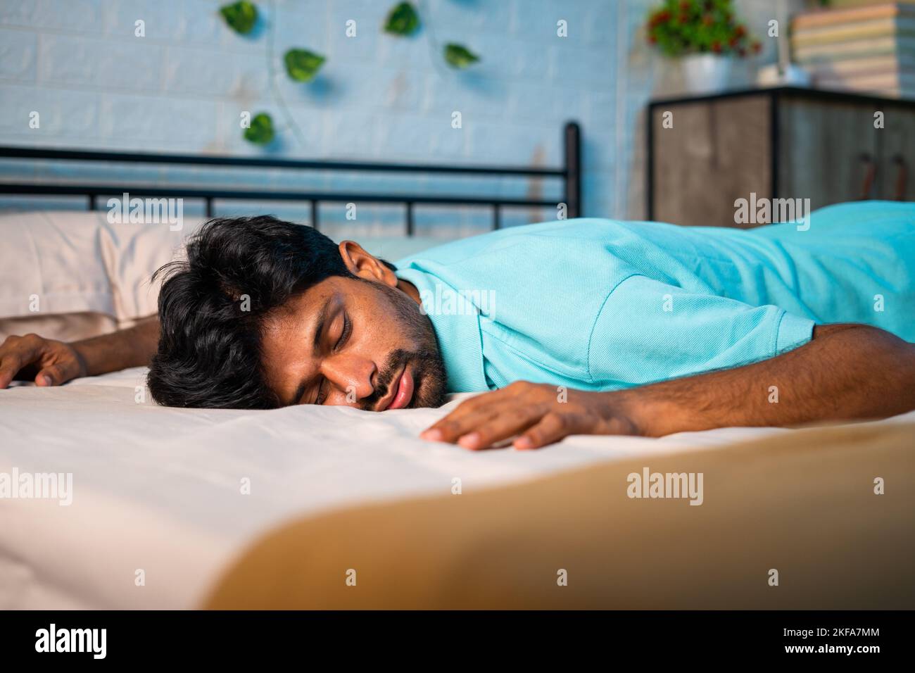 Abgestufte erschöpfte junge Mann im Schlafzimmer auf das Bett gefallen - Konzept der Müdigkeit, überarbeitet und Schlaflosigkeit Stockfoto