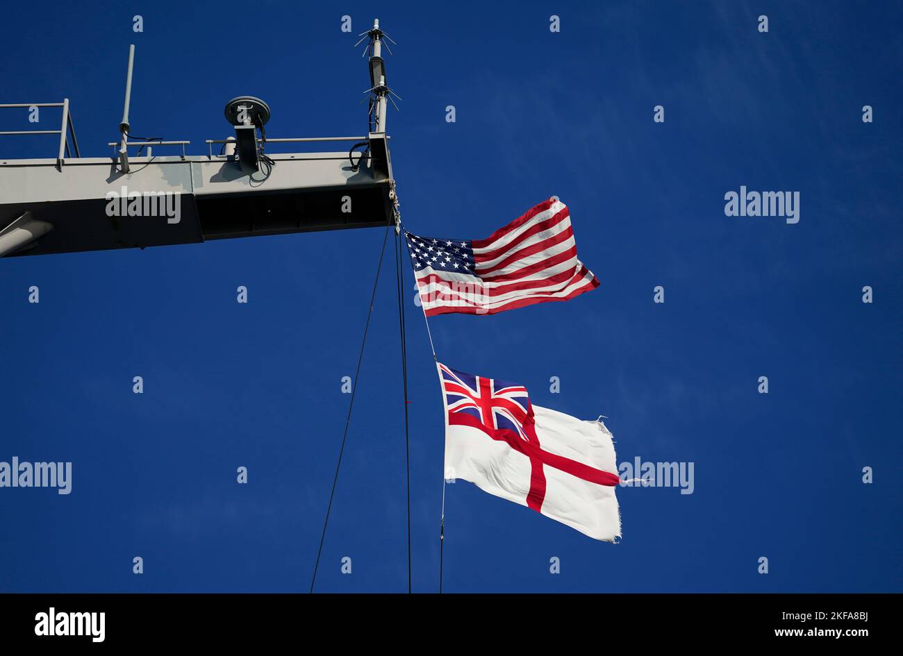 Die Flagge der Vereinigten Staaten von Amerika und das Fähnchen der Royal Navy fliegen von der USS Gerald R. Ford, dem 'größten Kriegsschiff der Welt', während eines Medienbesuchs, während es während eines Zwischenstopps in Portsmouth auf seinem Jungferneinsatz im Solent vor Anker liegt. Bilddatum: Donnerstag, 17. November 2022. Stockfoto