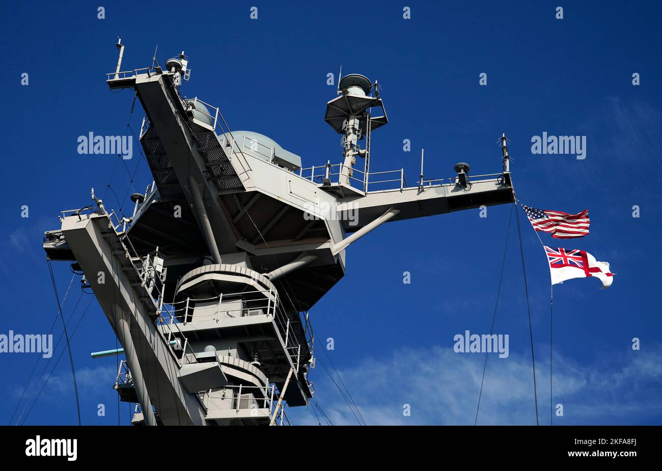 Die Flagge der Vereinigten Staaten von Amerika und das Fähnchen der Royal Navy fliegen von der USS Gerald R. Ford, dem 'größten Kriegsschiff der Welt', während eines Medienbesuchs, während es während eines Zwischenstopps in Portsmouth auf seinem Jungferneinsatz im Solent vor Anker liegt. Bilddatum: Donnerstag, 17. November 2022. Stockfoto